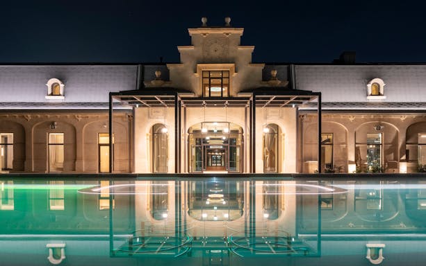 Milan spa exterior with illuminated pool at night.