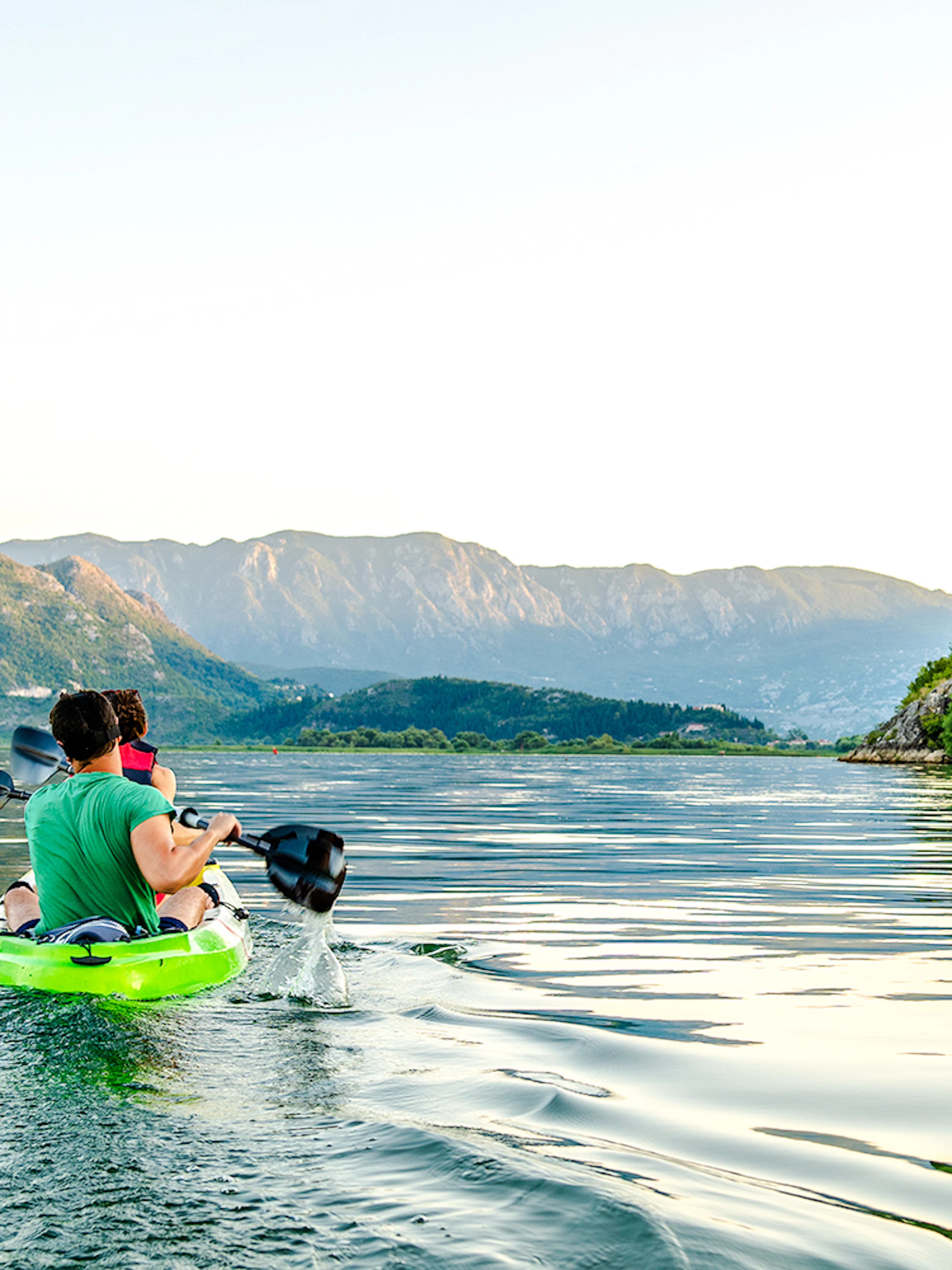 Kayakers paddling on Lake Skadar with mountainous landscape in Montenegro.