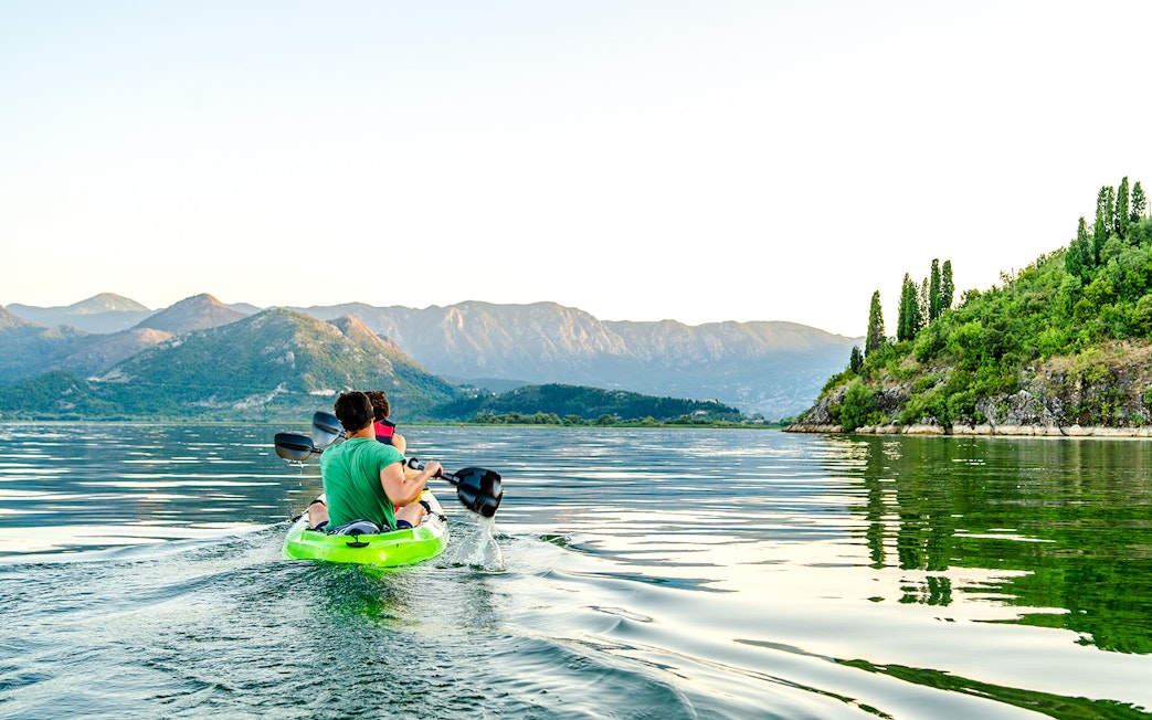 Kayakers paddling on Lake Skadar with mountainous landscape in Montenegro.