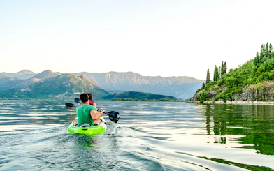 Kayakers paddling on Lake Skadar with mountainous landscape in Montenegro.