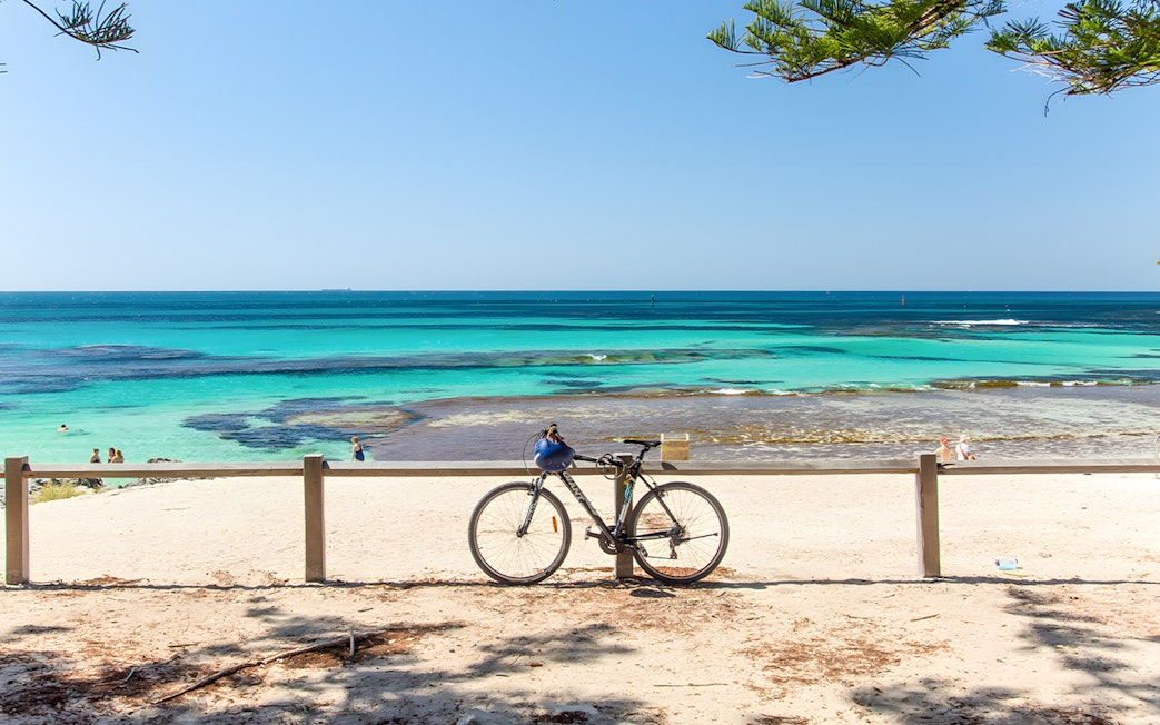 Bicycle parked on Rottnest Island beach with turquoise ocean view.