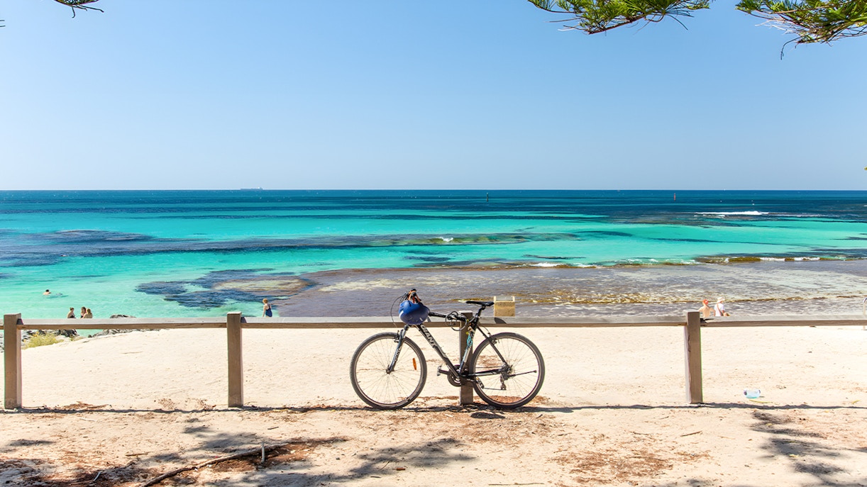 Bicycle parked on Rottnest Island beach with turquoise ocean view.