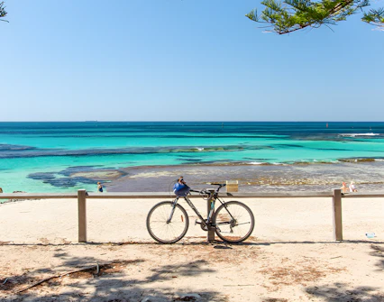 Bicycle parked on Rottnest Island beach with turquoise ocean view.