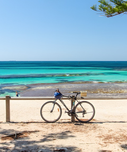 Bicycle parked on Rottnest Island beach with turquoise ocean view.