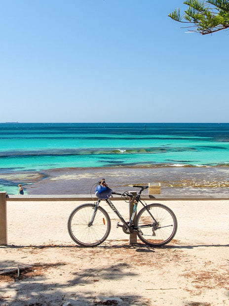 Bicycle parked on Rottnest Island beach with turquoise ocean view.
