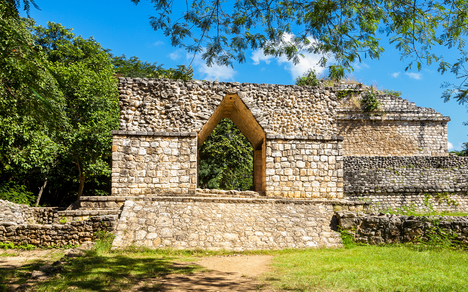 Entrance arch at Ek Balam ruins, Yucatan, Mexico, surrounded by lush greenery.