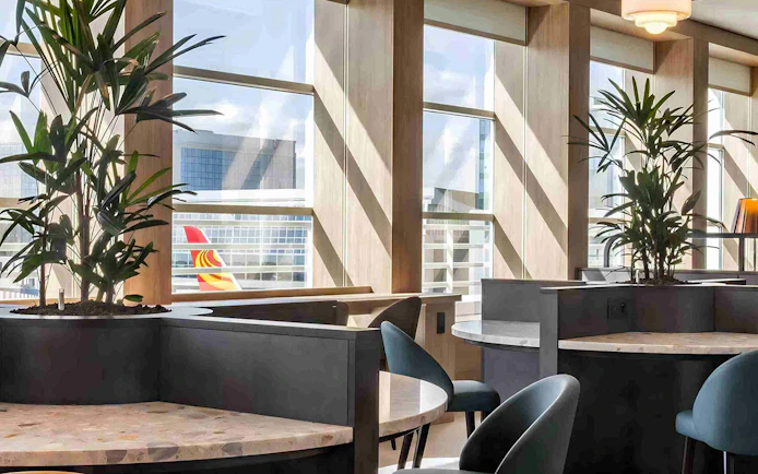 Brussels Airport lounge seating area with large windows and view of airplane tail.