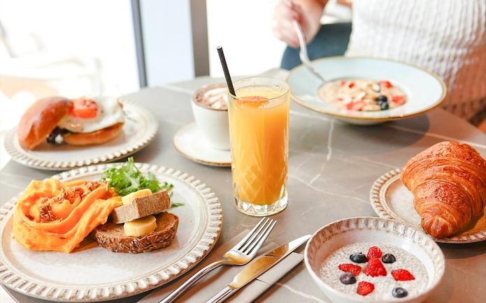 Breakfast spread at Sky Garden with croissant, chia pudding, orange juice, and bread with cheese.