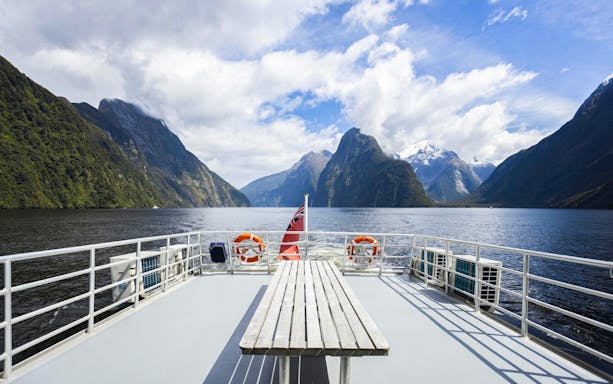 Cruise deck view of Milford Sound fjords in New Zealand with clear skies.