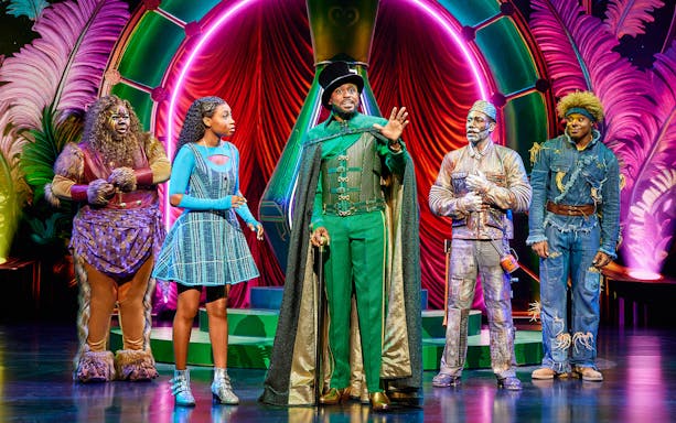 Cast of The Wiz performing on stage in colorful costumes.