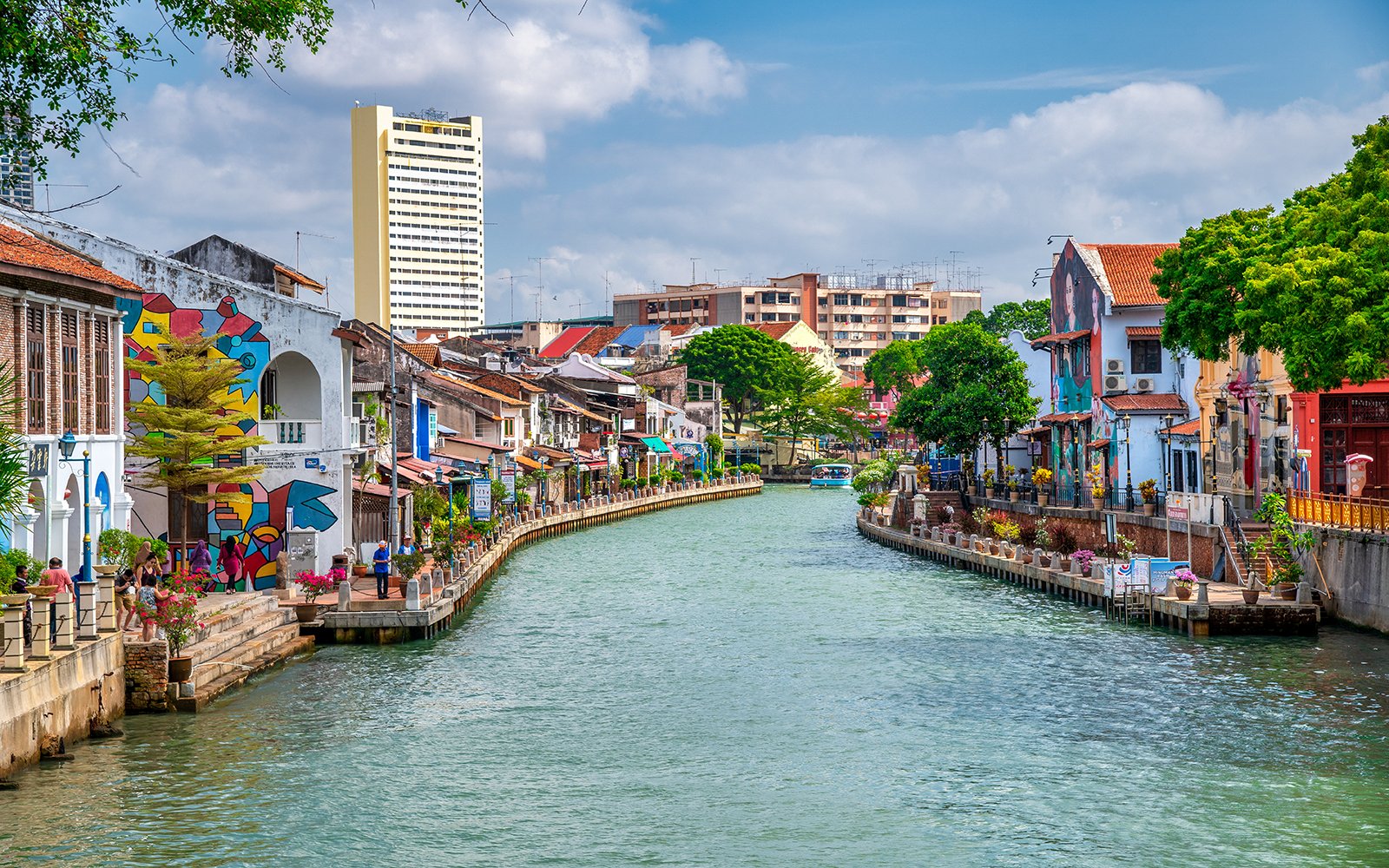 Melaka River with colorful buildings and murals on a sunny day.