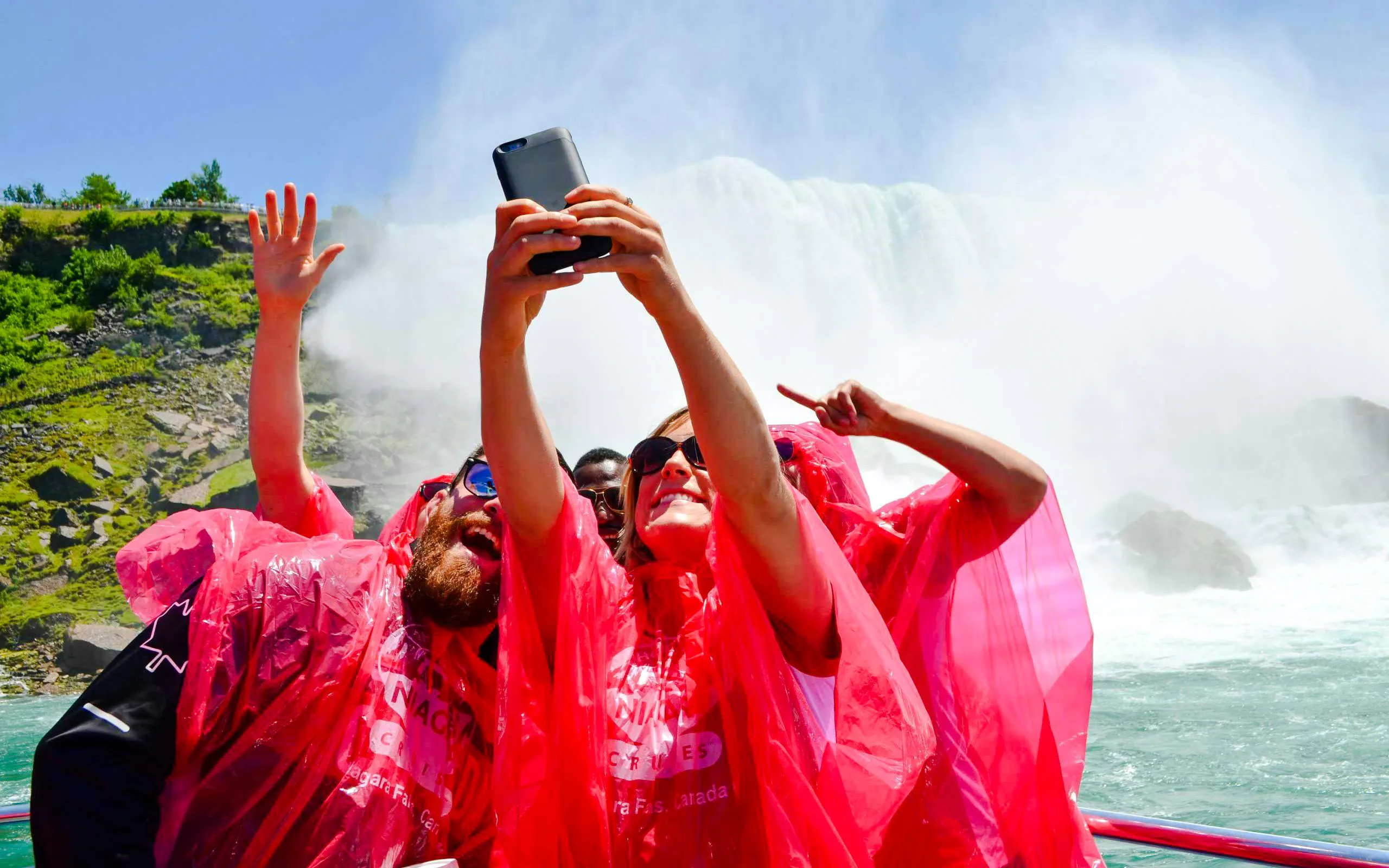 Tourists in red ponchos taking a selfie on a boat near Niagara Falls, Canada.