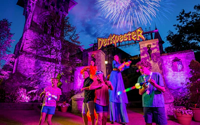 Busch Gardens Williamsburg Darkoaster ride with fireworks and performers at night.