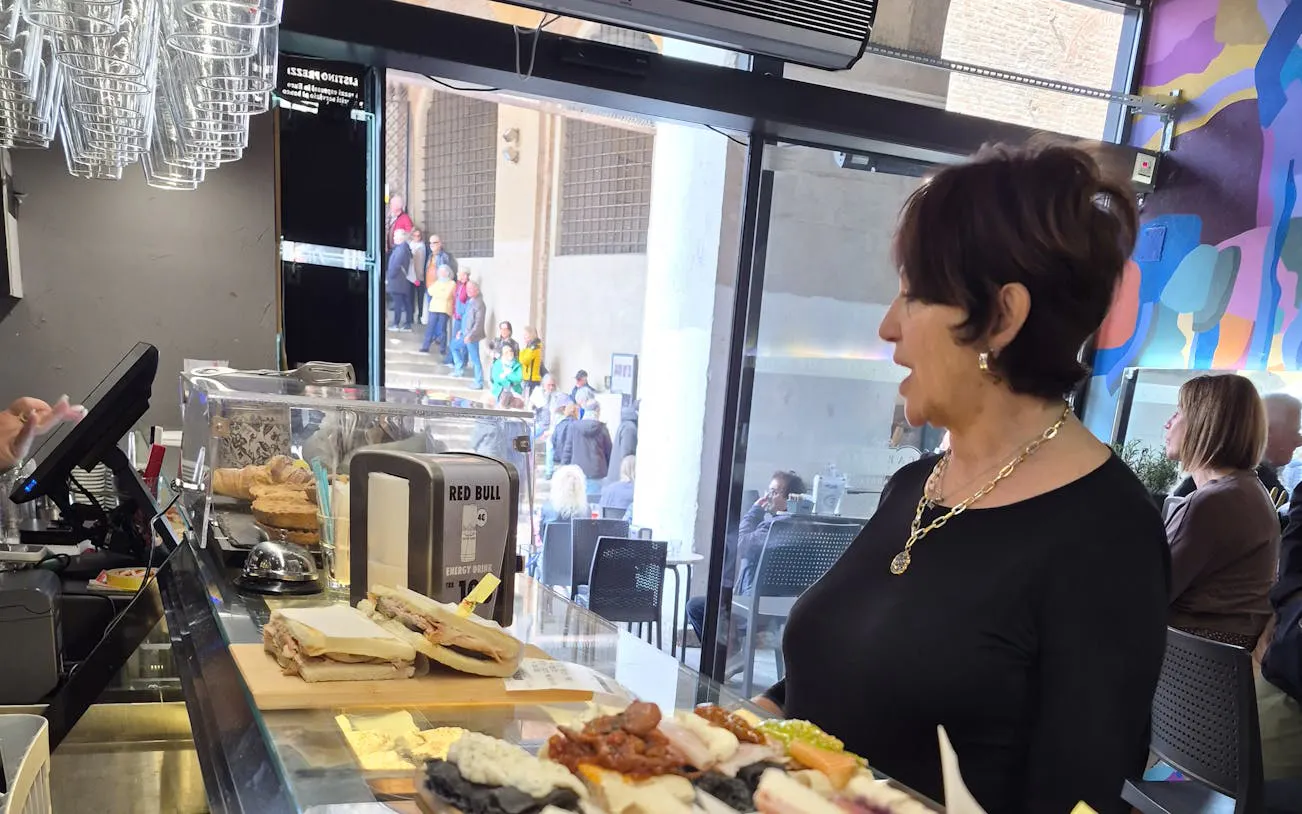 Woman at a counter with sandwiches and pastries during Padova Market to Osteria Food Tour.