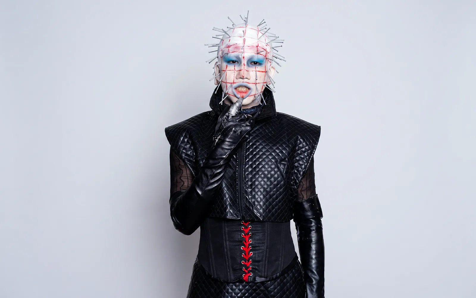 Hellraiser-inspired costume with pins and black leather outfit for Halloween.