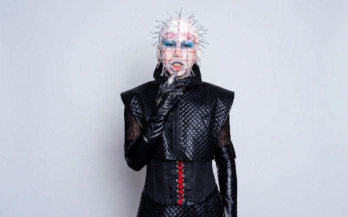 Hellraiser-inspired costume with pins and black leather outfit for Halloween.