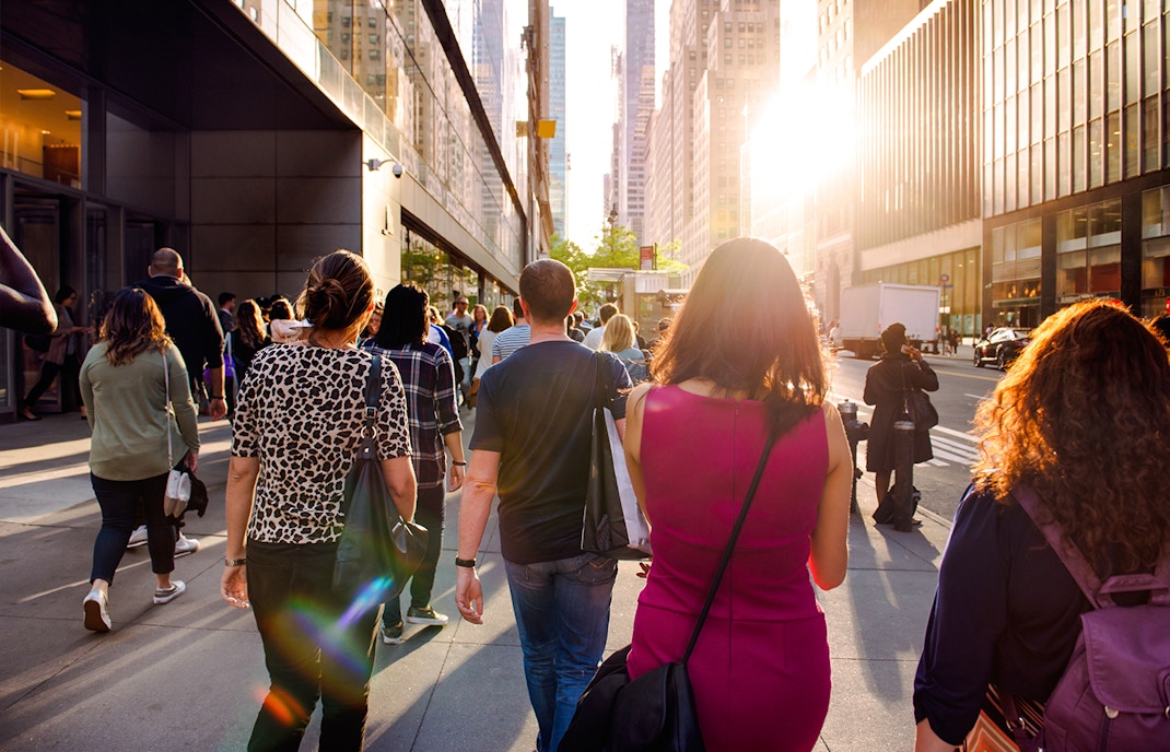 People walking on a sunny street in New York City during Empire State Building tour.
