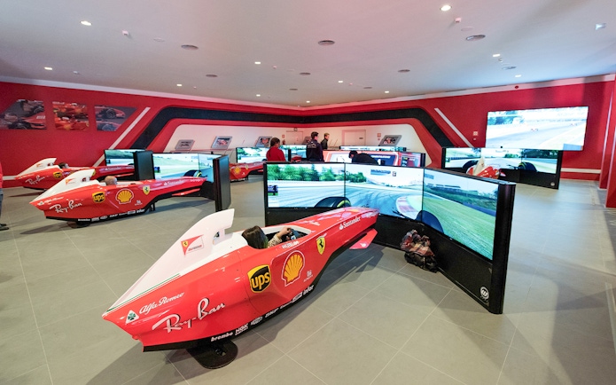 F1 simulators at Ferrari Land with people experiencing virtual racing.