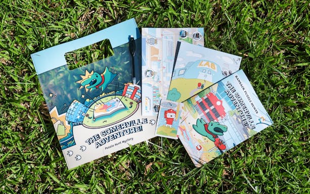 Ransack's "The Somerville Adventure" puzzle hunt kit on grass.