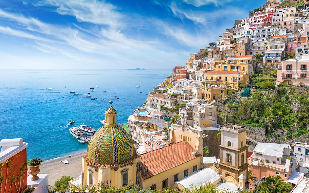 Panoramic view of Positano's colorful cliffside buildings and dome, Amalfi Coast.