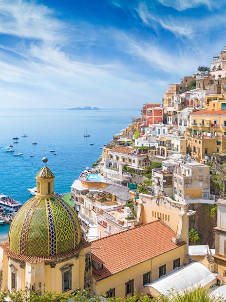 Panoramic view of Positano's colorful cliffside buildings and dome, Amalfi Coast.