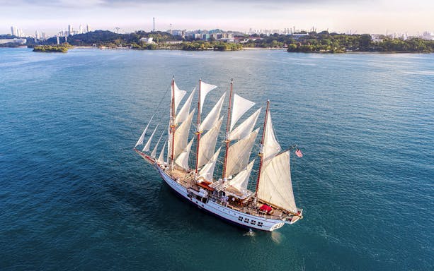 Royal Albatross ship sailing at sunset with guests dining on deck, Singapore.