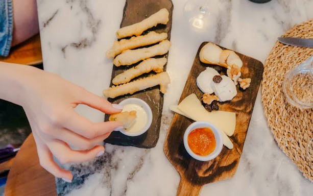 Cheese board with traditional Lisbon dishes, including cheese, nuts, and dipping sauces.