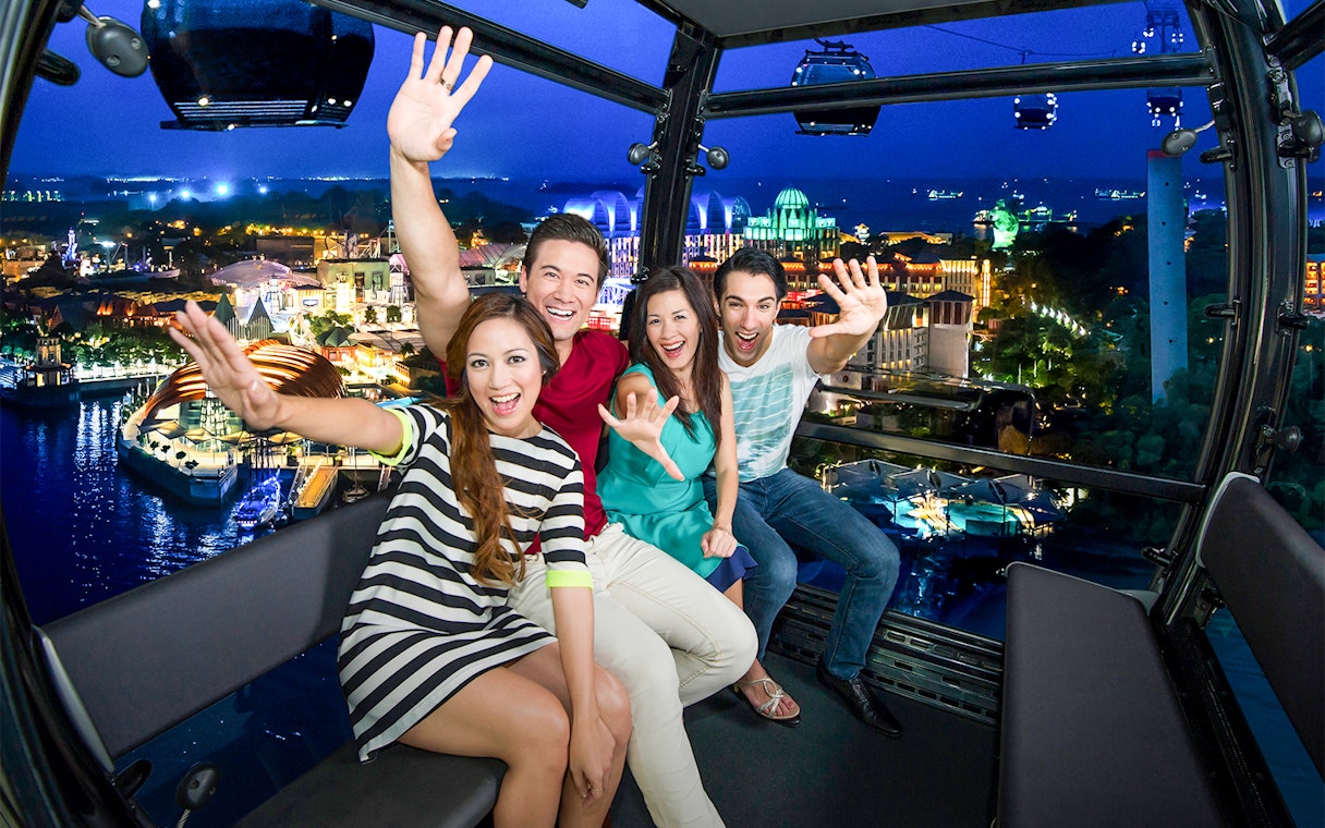 Group of friends enjoying night view from Singapore Cable Car, part of Singapore Unlimited Attractions Day Pass.