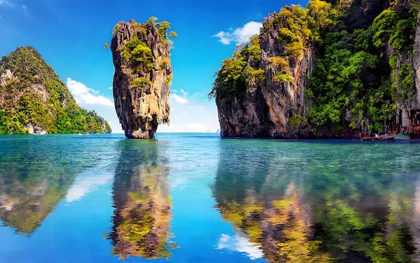 Limestone karst formations in Phang Nga Bay, Thailand, with clear blue water.