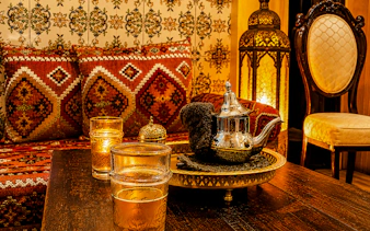 Moroccan tea set on a table with ornate cushions and lantern in Marrakesh hammam.