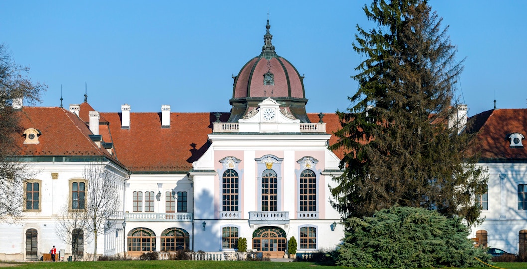 Royal Palace of Godollo facade with clock tower and red roof.