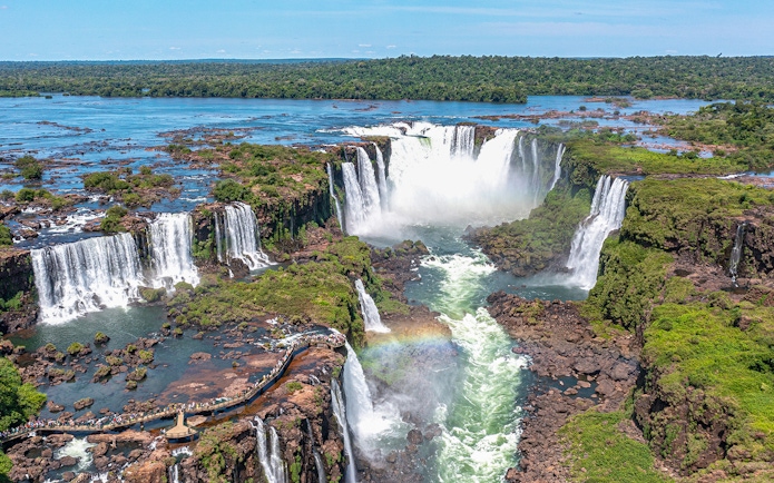 Aerial view of Iguazu Falls with a rainbow and lush greenery.