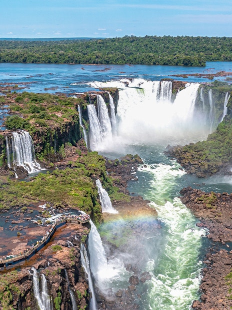 Aerial view of Iguazu Falls with a rainbow and lush greenery.