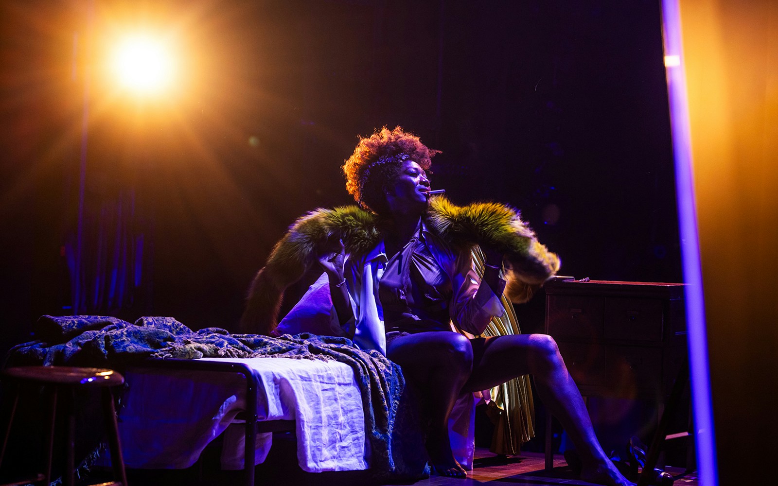 Performer on stage under spotlight, wearing a fur-trimmed coat, related to Lempicka.