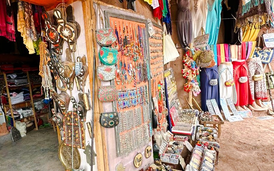 Market stall with colorful jewelry and traditional clothing in Merzouga, Morocco.