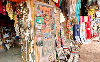 Market stall with colorful jewelry and traditional clothing in Merzouga, Morocco.