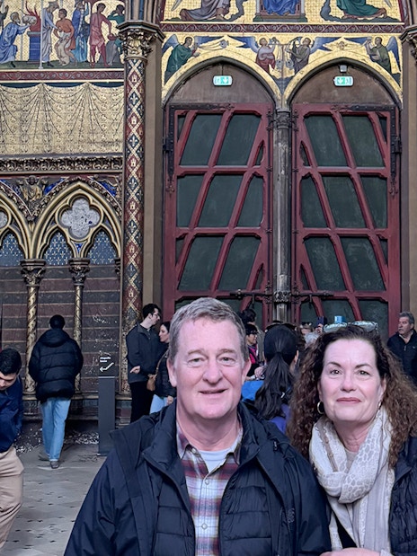 Visitors inside Sainte Chapelle, Paris, with ornate stained glass and Gothic architecture.