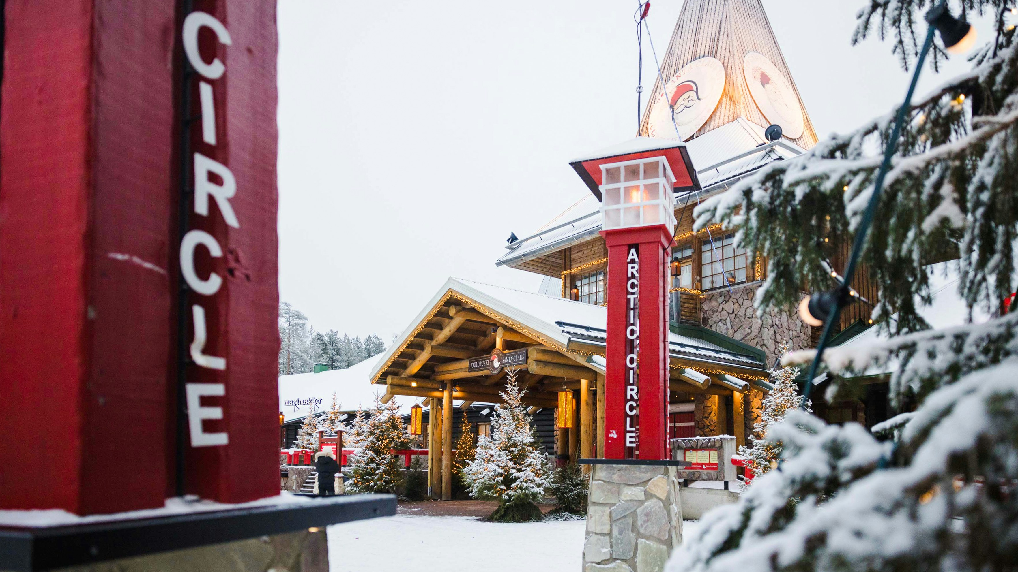 Santa Claus Village entrance with Arctic Circle sign in snowy Lapland.