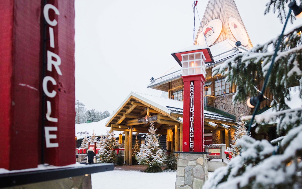 Santa Claus Village entrance with Arctic Circle sign in snowy Lapland.