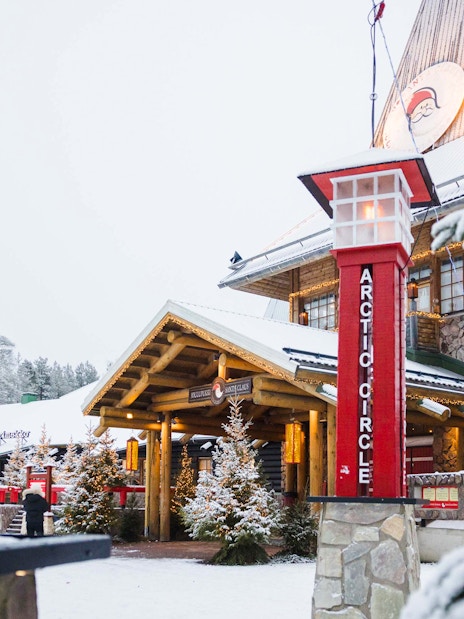 Santa Claus Village entrance with Arctic Circle sign in snowy Lapland.