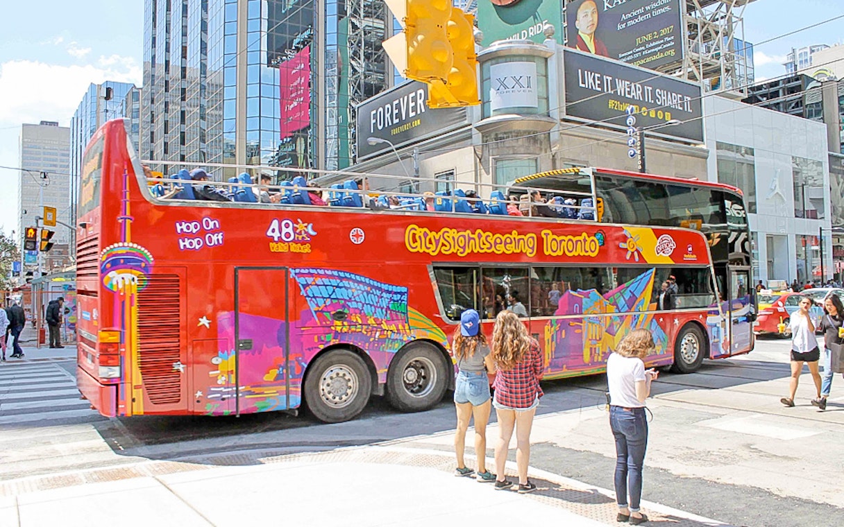Toronto sightseeing bus at downtown stop with passengers boarding.