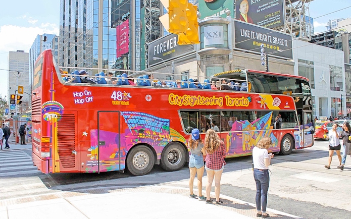 Toronto sightseeing bus at downtown stop with passengers boarding.