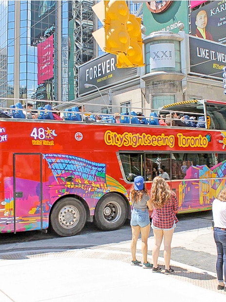 Toronto sightseeing bus at downtown stop with passengers boarding.
