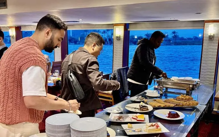 Guests serving themselves at a buffet on a Cairo Nile dinner cruise.