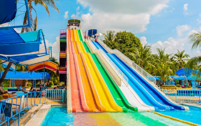 Colorful water slides at Aqualand with palm trees and blue sky.
