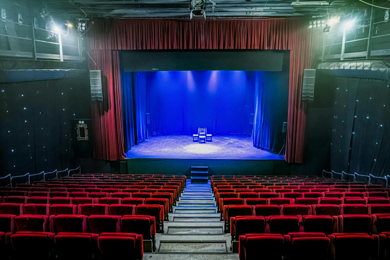 Interior of Teatro Flamenco Sevilla with empty red seats facing a lit stage.