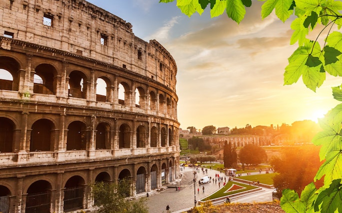 Colosseum in Rome at sunset with tourists exploring the area.