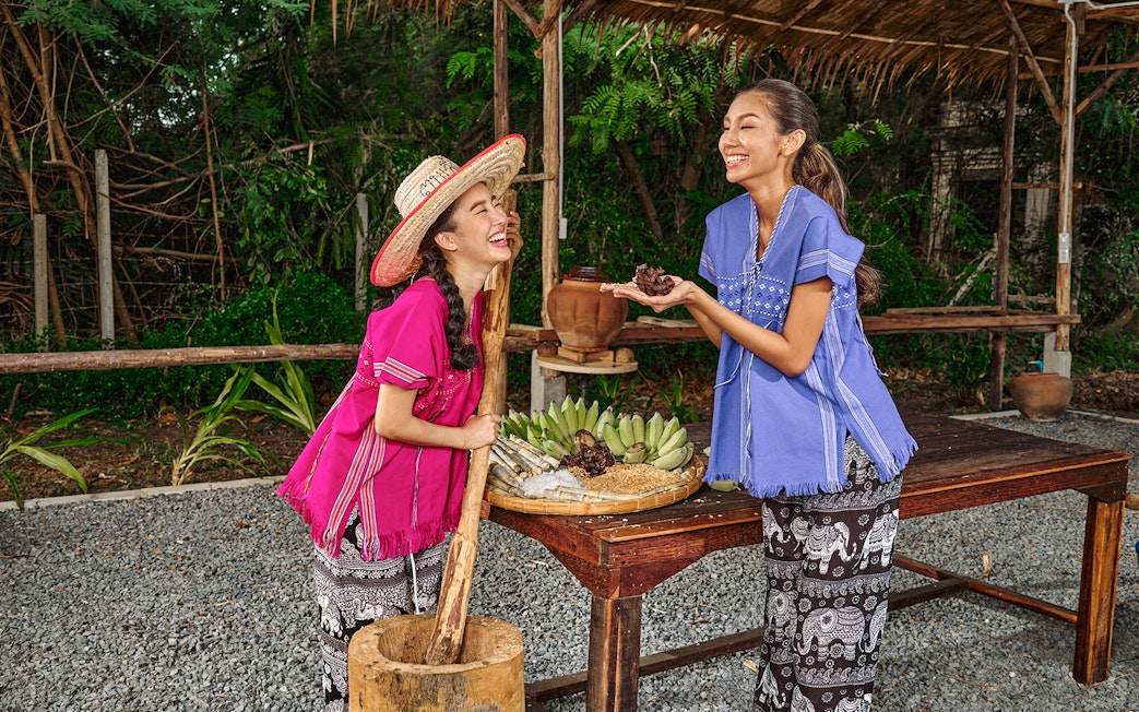 Women in traditional attire preparing food at Bangkok Elephant Park.