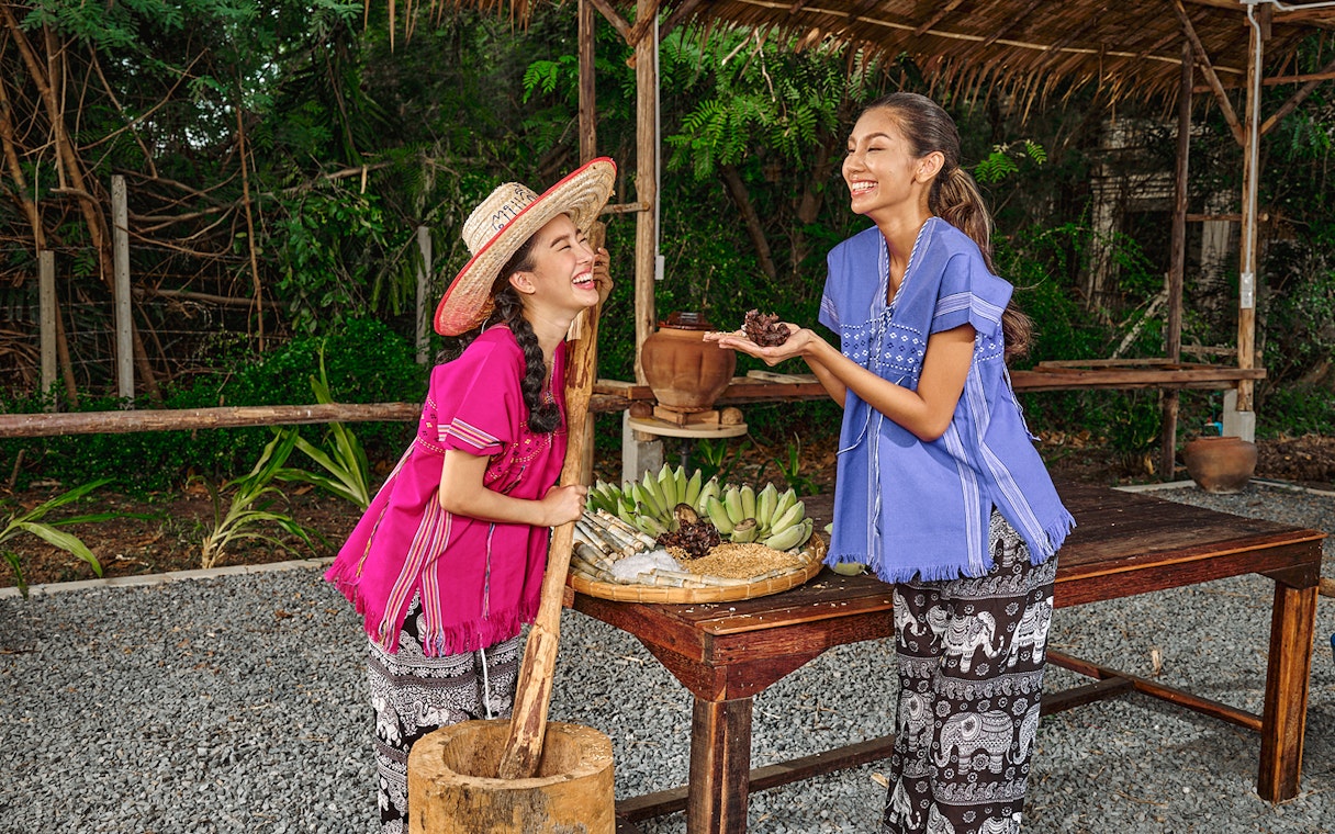 Women in traditional attire preparing food at Bangkok Elephant Park.