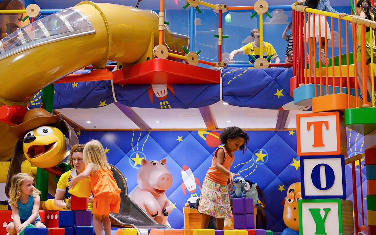 Kids playing in a Disney-themed club with colorful toys and slides on a Disney Adventure Cruise.